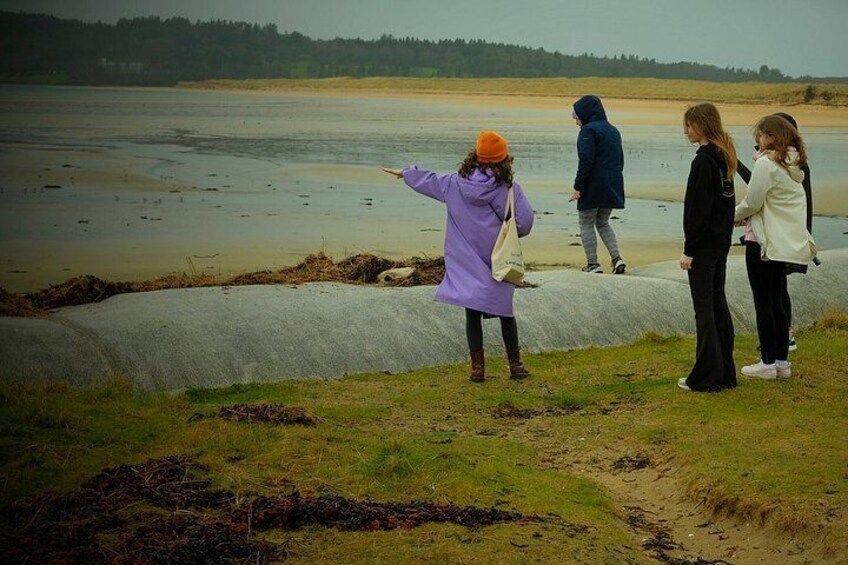 A group of people standing by a riverbank, with one person pointing towards the water. 5