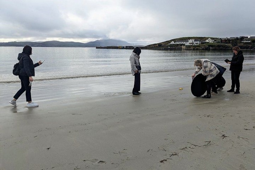 A beach with people walking and a person carrying a large object. 4
