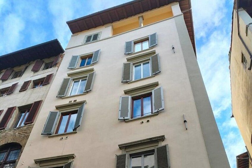 A multi-story building with a beige facade and green shutters. 5