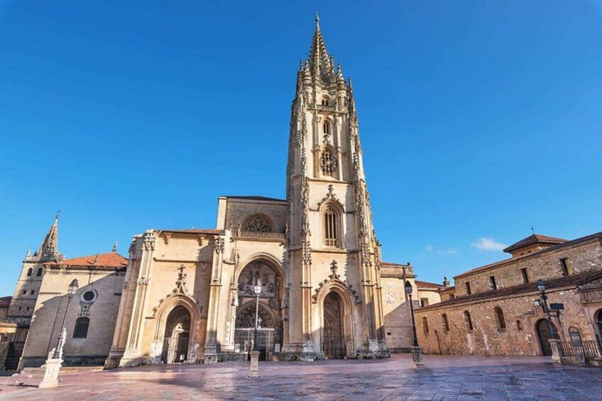 Una catedral histórica con una aguja alta, una entrada de arco grande y un patio. 1