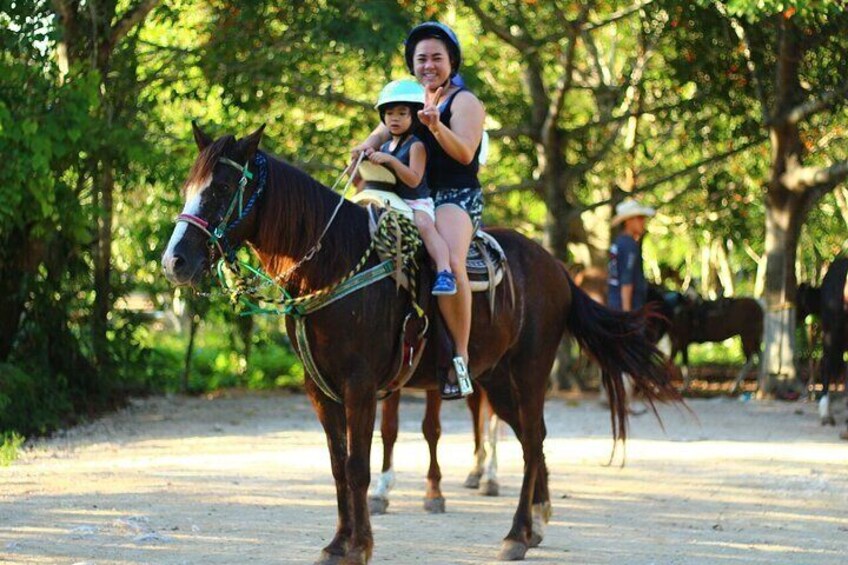 A person riding a horse on a dirt path with trees in the background. 5