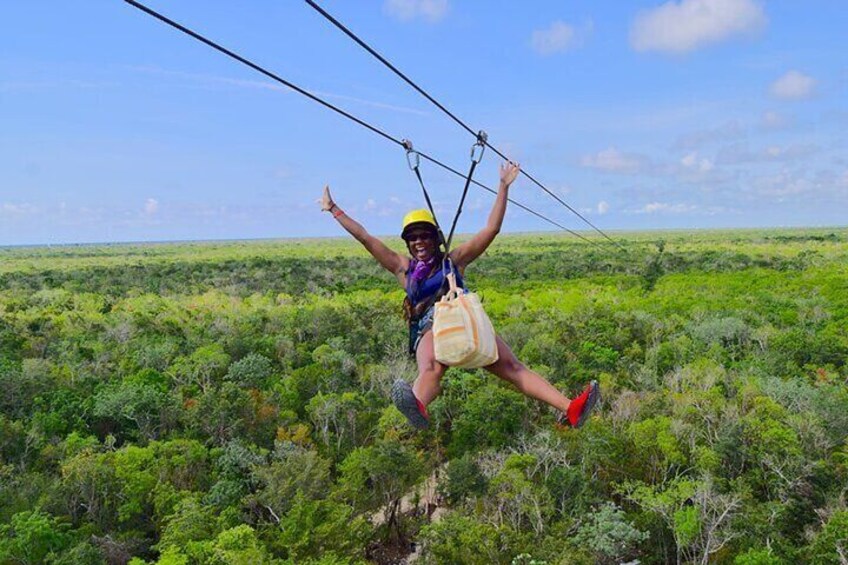 A person ziplining over a dense green forest. 3