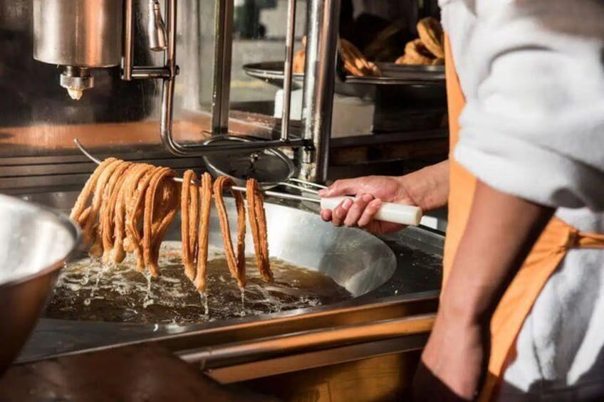 Eine Person brät Churros in einer Fritteuse. 2