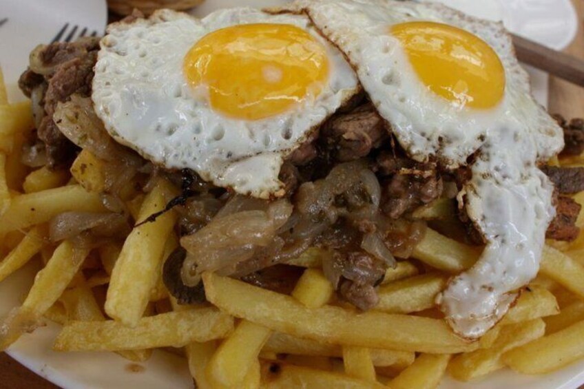 Eine Portion Pommes Frites mit Spiegeleiern und Rindfleisch. 3