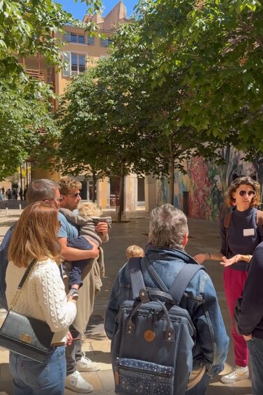 A group of people standing in a courtyard with trees and a building in the background. 2