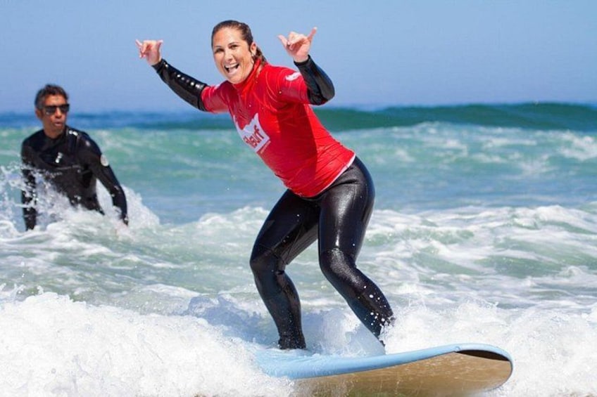 A person surfing on a wave with another person in the background. 1