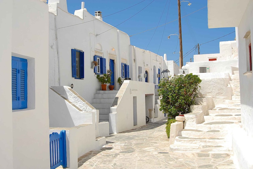 A narrow white-washed street with blue shutters, stone steps, and a clear blue sky. 3