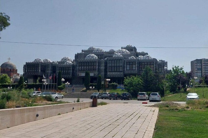 A modern building with a unique dome structure, surrounded by a paved area with cars and greenery. 5