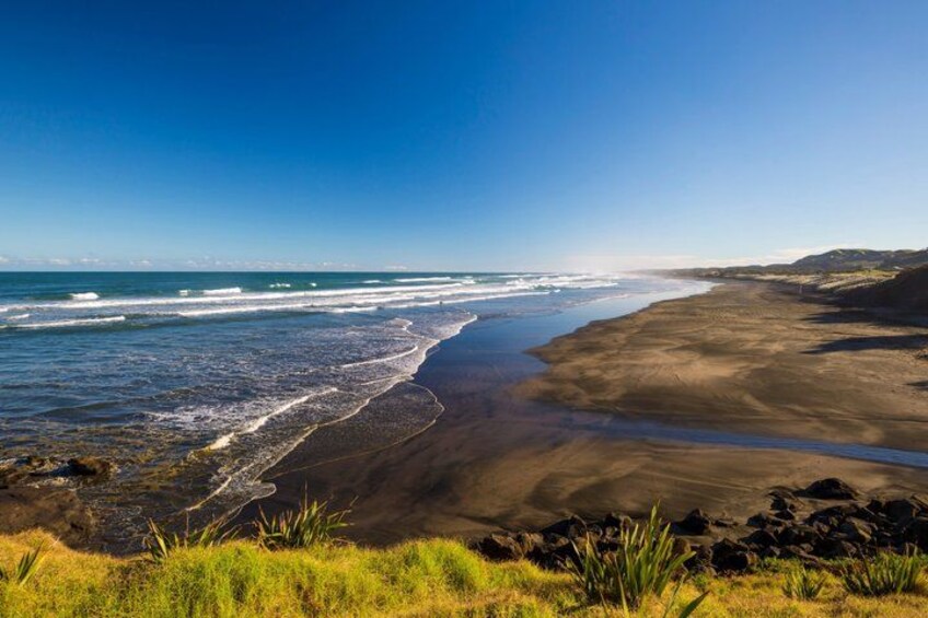 A beach with waves, a sandy shore, and rocky outcrops. 2