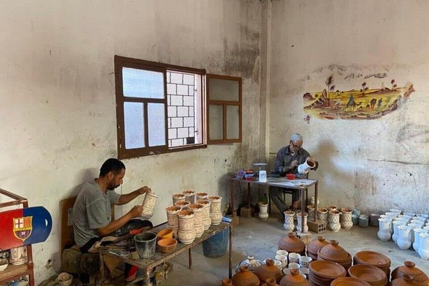 Et keramikværksted med to kunsthåndværkere, der arbejder på lerpotter. 2