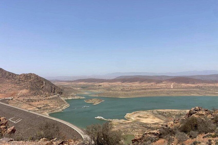 Un río serpentea por un paisaje desértico con montañas al fondo y una presa a la izquierda. 5
