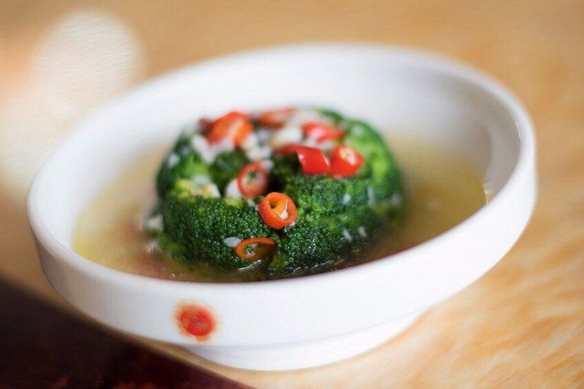 A bowl of soup with a green vegetable and red chili slices. 3