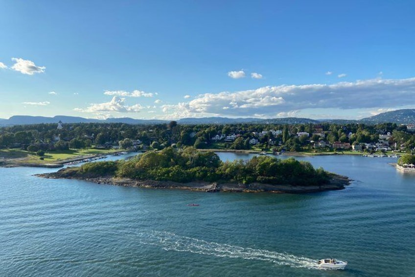 Un lac avec une petite île, un bateau et une rive lointaine bordée de bâtiments. 1