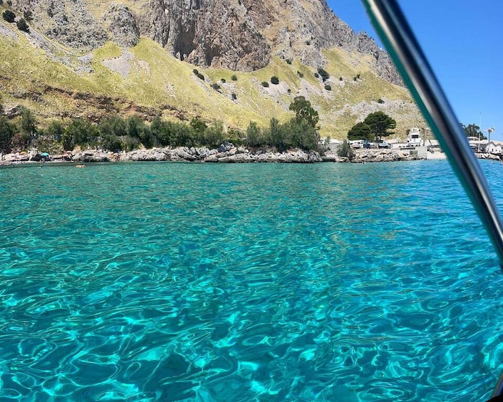 Clear turquoise water, rocky coastline, and a mountain in the background. 4