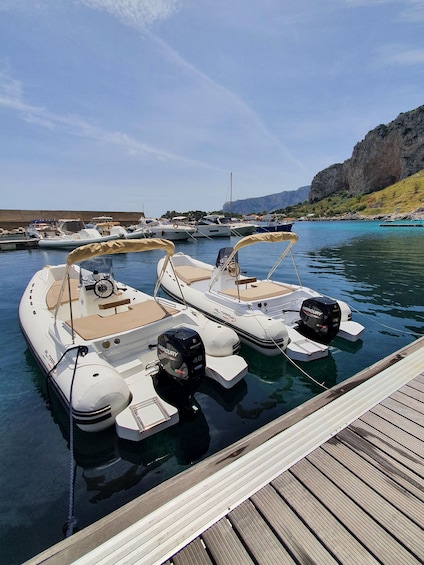 A marina with several boats docked, a wooden dock, and a rocky cliff in the background. 3