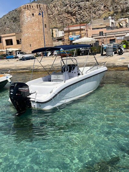 A white motorboat with a Mercury outboard motor docked at a marina. 2
