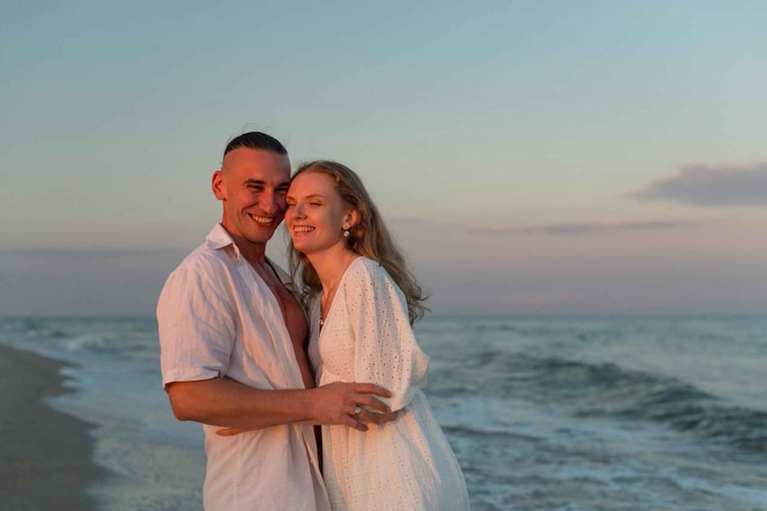 A couple embracing on a beach with the ocean in the background. 2