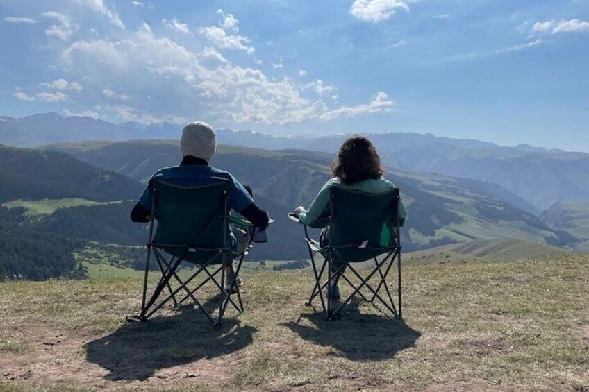 Dos personas en sillas plegables contemplando un paisaje montañoso. 1