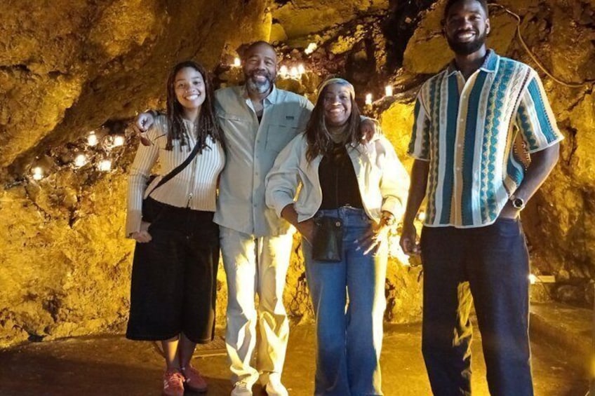 A group of people standing in a cave with illuminated string lights. 5