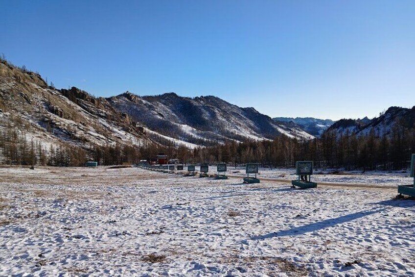 Un paisaje nevado con montañas, cielo despejado y varios carteles informativos. 5