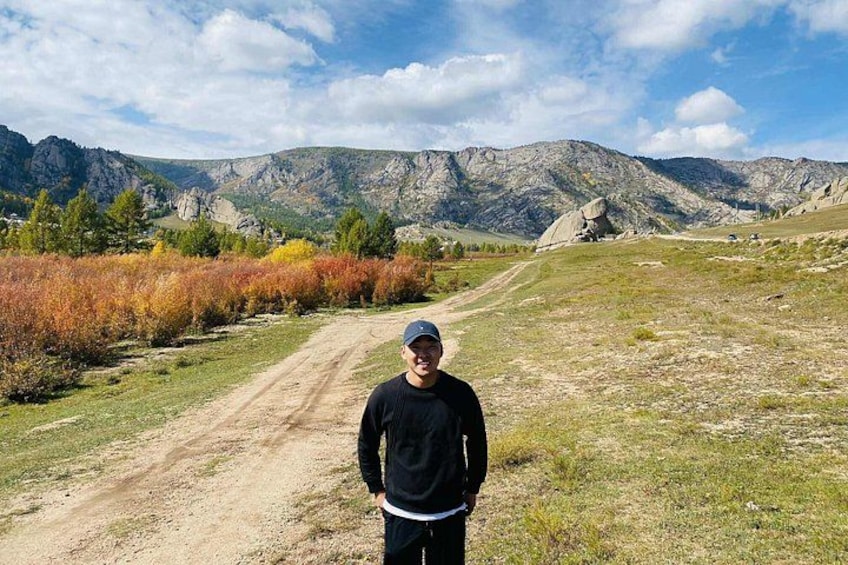 Una persona de pie en un sendero de tierra con montañas al fondo. 1