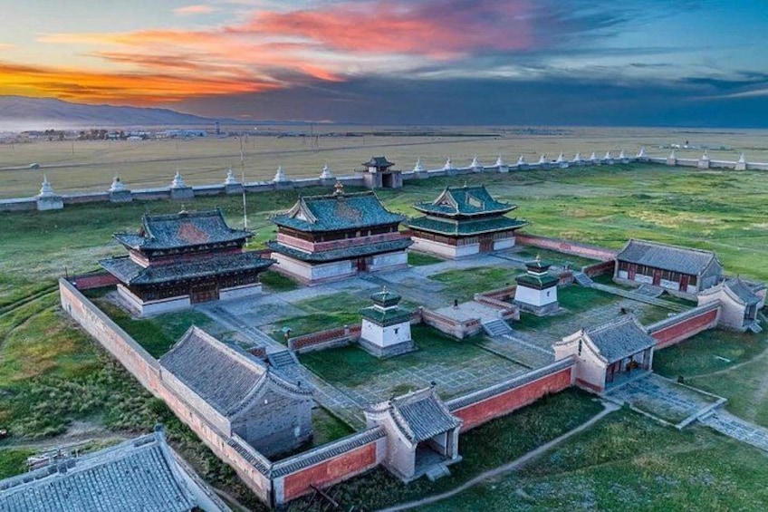 A traditional Chinese architectural complex with multiple buildings, a large open field, and a distant view of a body of water. 1