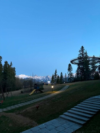 A park with a slide, a circular structure, and snow-capped mountains in the background. 3