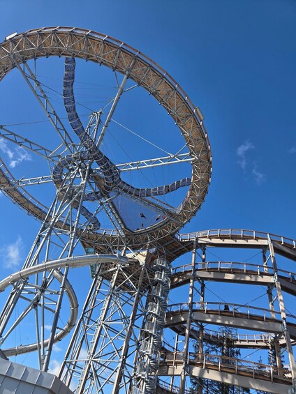A large Ferris wheel with multiple gondolas, a metal framework, and a clear blue sky. 1