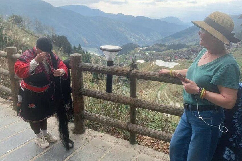 Two people standing by a wooden fence overlooking a mountainous landscape. 2