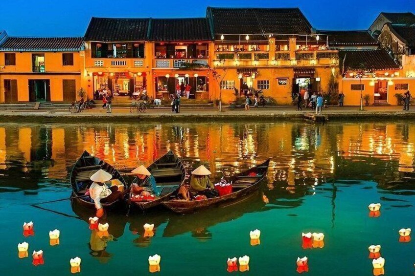 Traditionele boten met passagiers, een rivier en een gebouw met verlichte ramen. 1