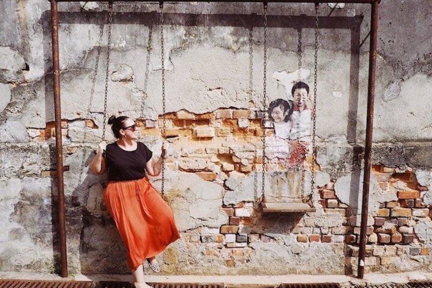 A person on a swing with a brick wall in the background. 3
