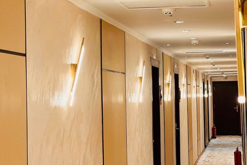 A hallway with wooden paneling, recessed lighting, and a fire extinguisher. 2