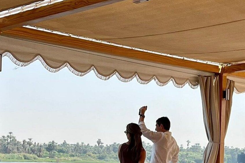 A couple under a canopy overlooking a landscape with trees and a clear sky. 3