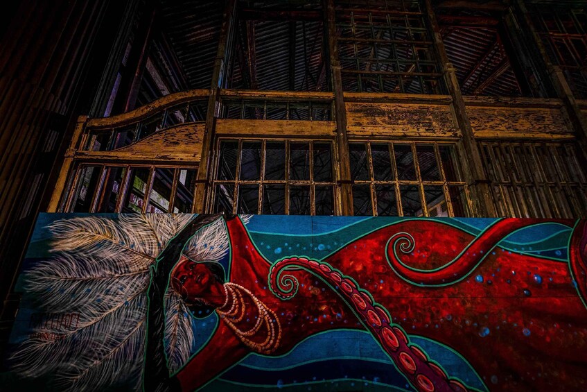A traditional wooden structure with a mural of a red octopus and a feather. 5
