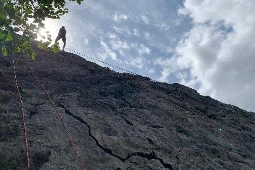 A person rappelling down a rocky cliff with a rope. 2
