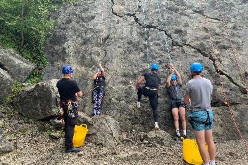 A group of people climbing a rocky cliff with safety gear and ropes. 1