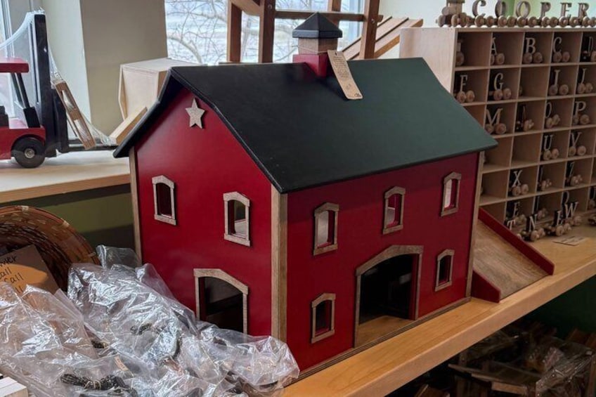 A red and green model house with a star on the roof, surrounded by alphabet blocks and a toy forklift. 5