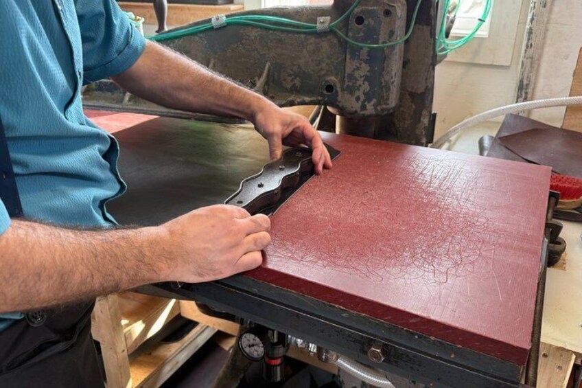 A person using a machine to cut a red material. 1