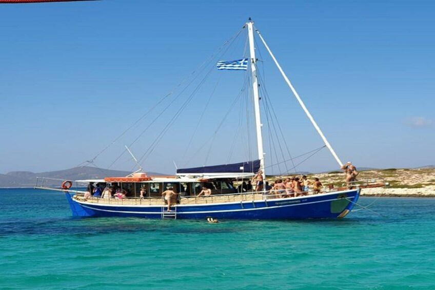 A blue boat with people on board, anchored in clear turquoise water with a coastline in the background. 2