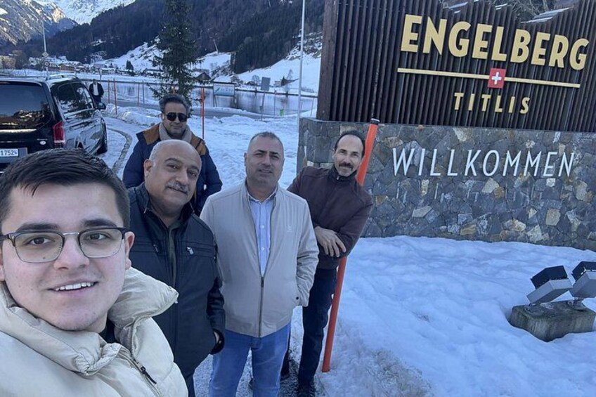 A group of people standing in front of a sign that reads 'Engelberg Titsis' with a welcome message. 4
