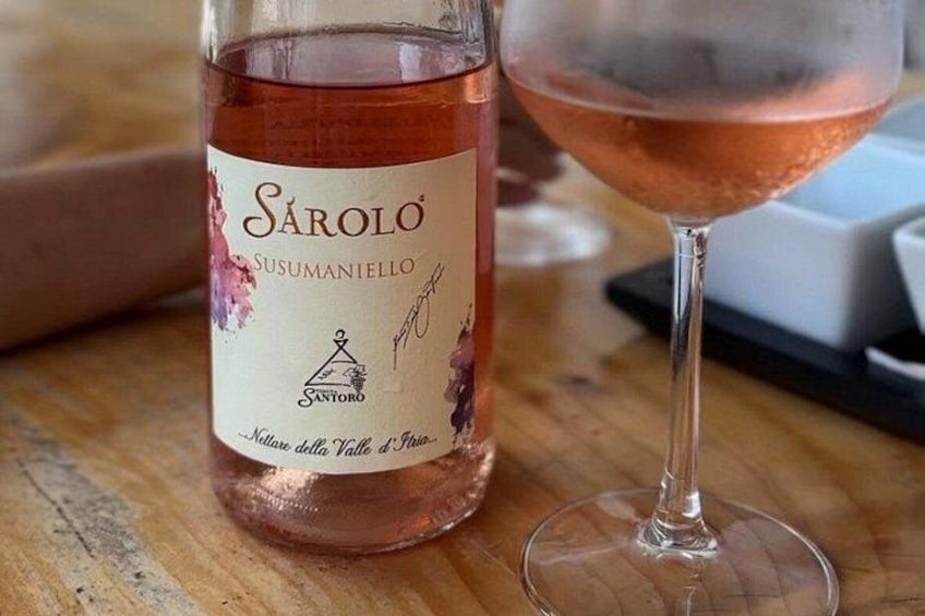 Een fles Saroło wijn en een glas wijn op een houten ondergrond. 5