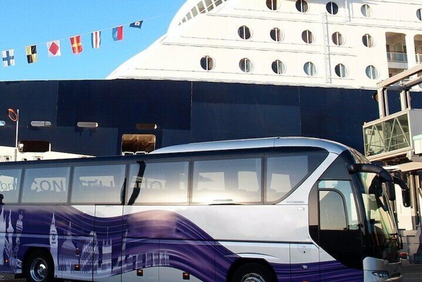 A bus with a wave design parked in front of a large building with circular windows. 2