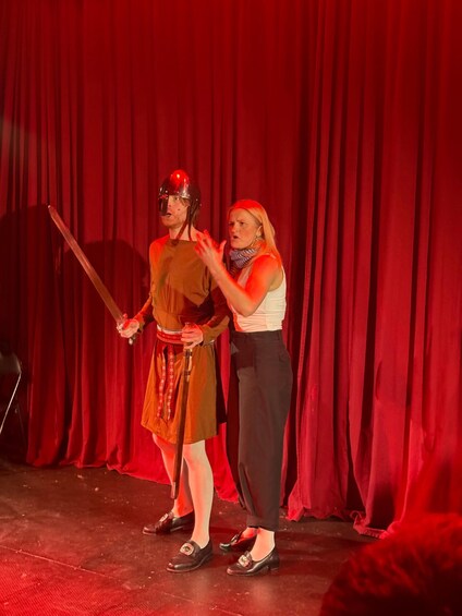 Two people on a stage with a red curtain backdrop. 5