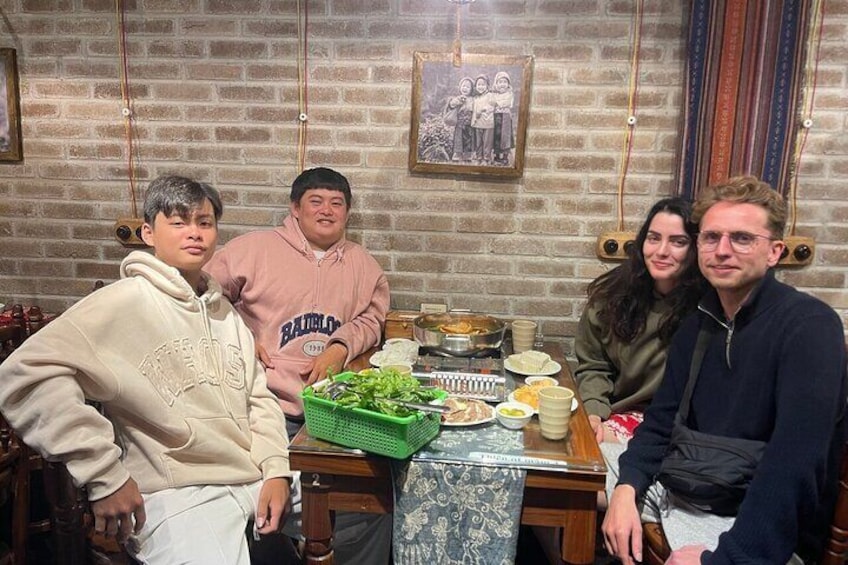 A group of people sitting around a table with food and drinks. 5