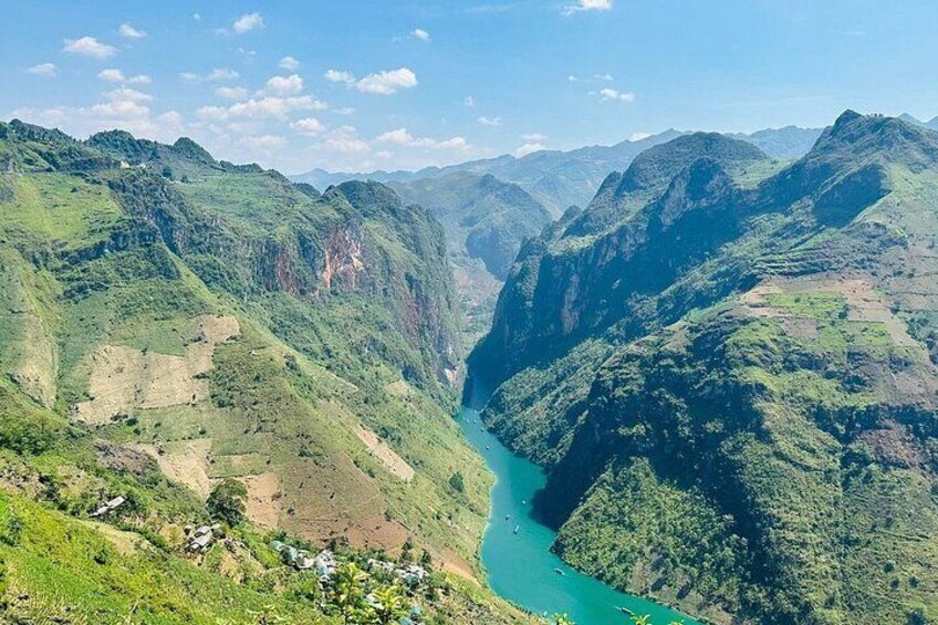 A river winding through a mountainous valley with lush greenery and scattered houses. 2