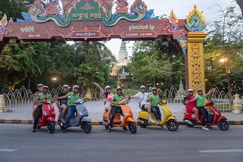 A group of people on scooters at a temple entrance. 5