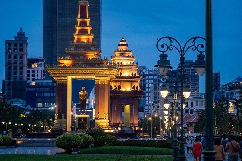 Un complejo de templos bien iluminado con una pagoda destacada, rodeado de edificios modernos y un parque con una fuente. 1