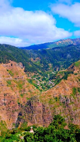 A mountainous landscape with a valley, a small church, and a clear blue sky. 2