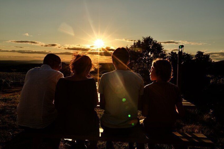 A sunset with a group of people sitting on a grassy area. 4