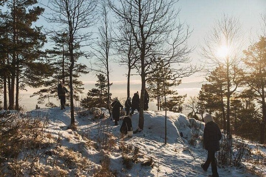 A group of people hiking in a snowy forest with trees and a clear sky. 1